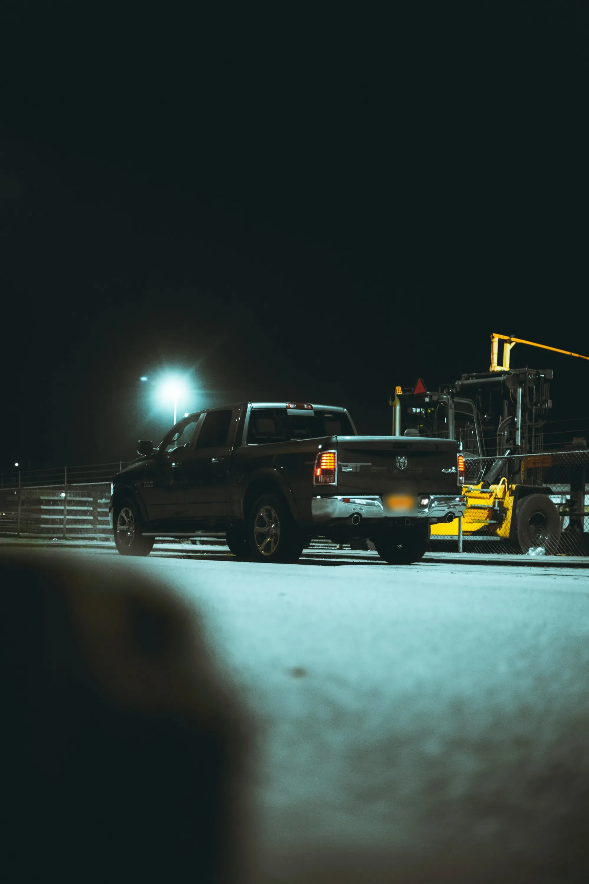 Pickup truck parked beside equipment under a bright light at night
