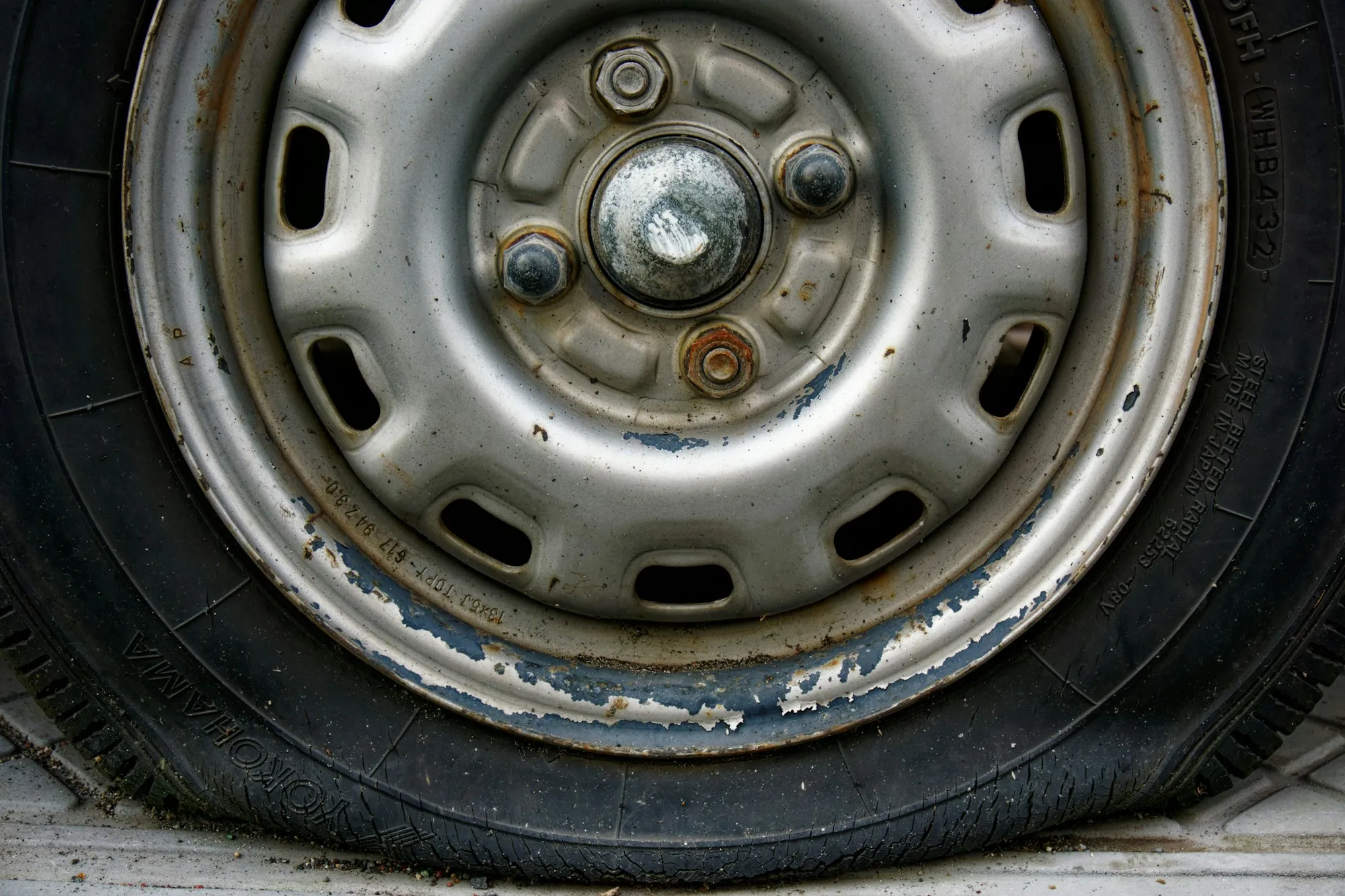 Close view of a flat, worn tire on a steel wheel