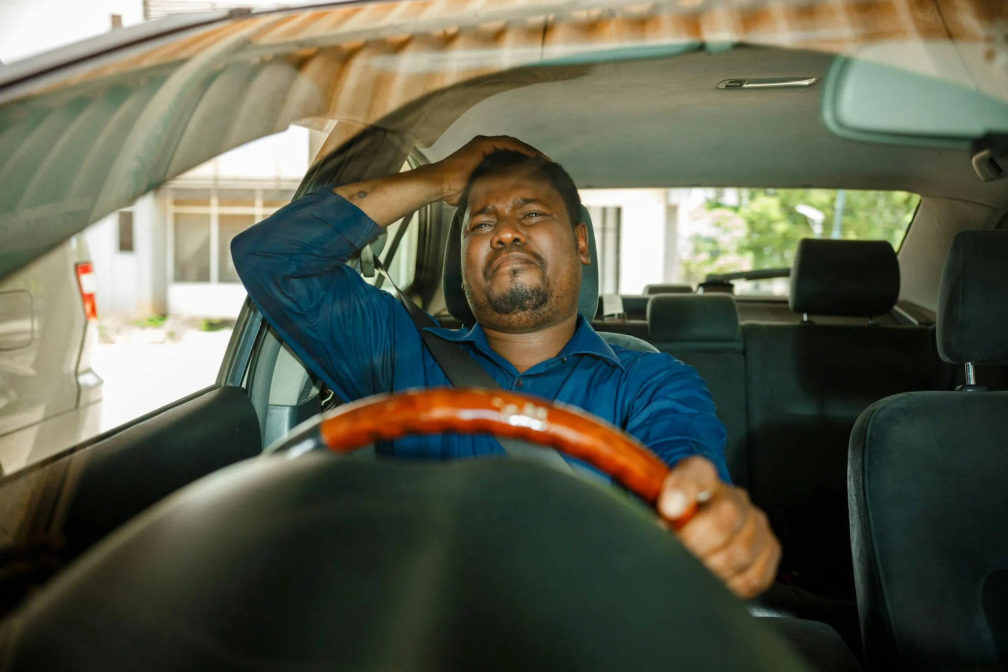 Stressed driver holding his head while sitting behind the steering wheel