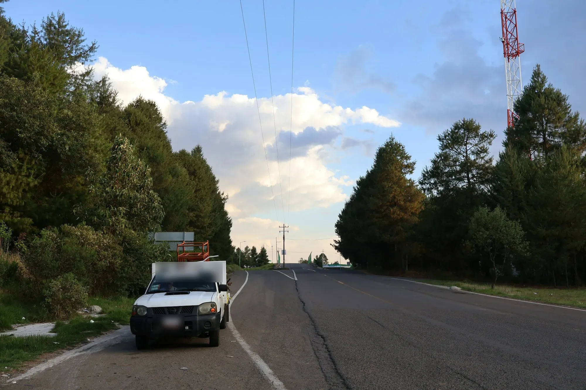 Car driving along an open two-lane road under a wide sky