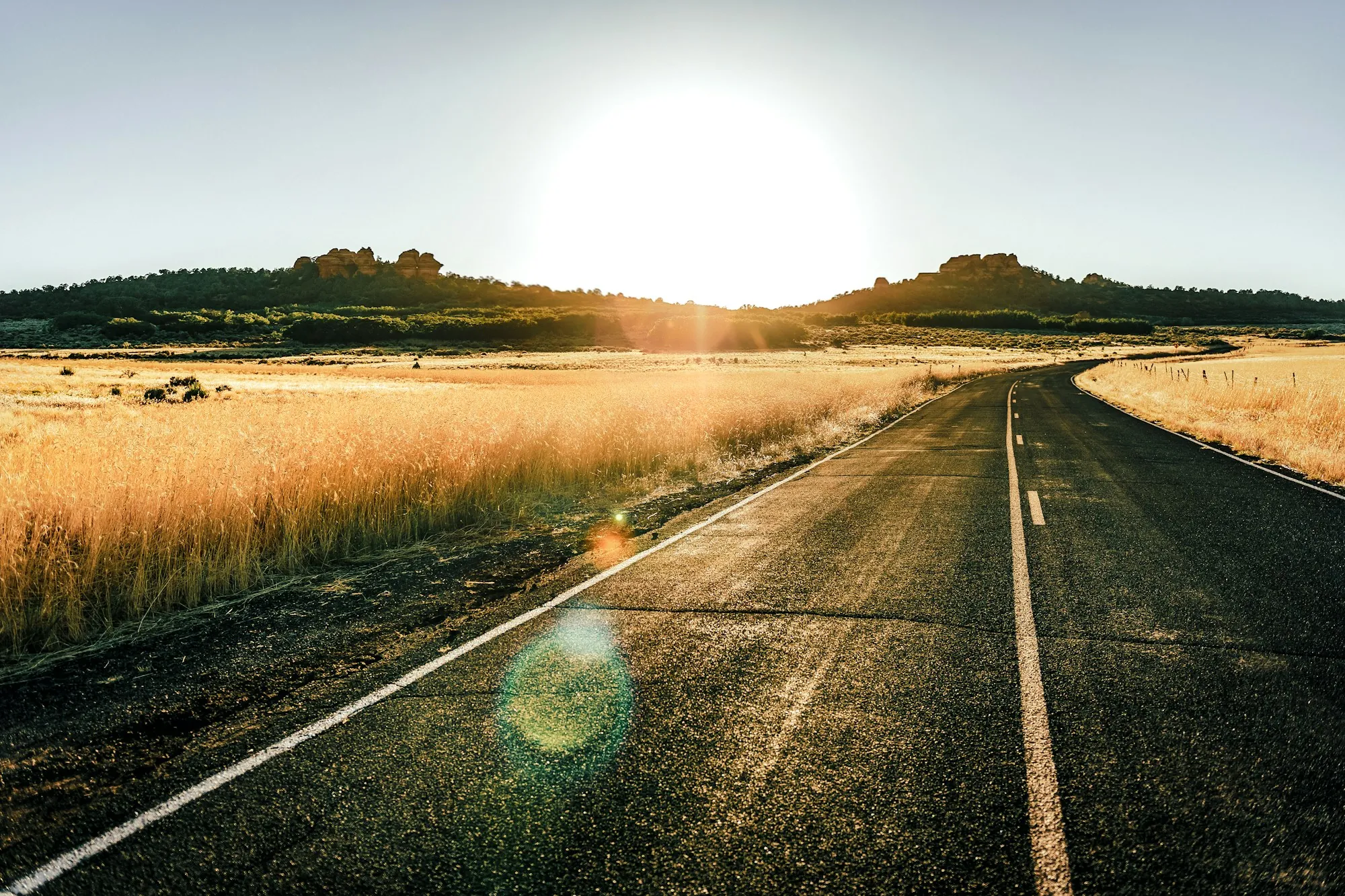 Straight country road running toward the horizon at sunset