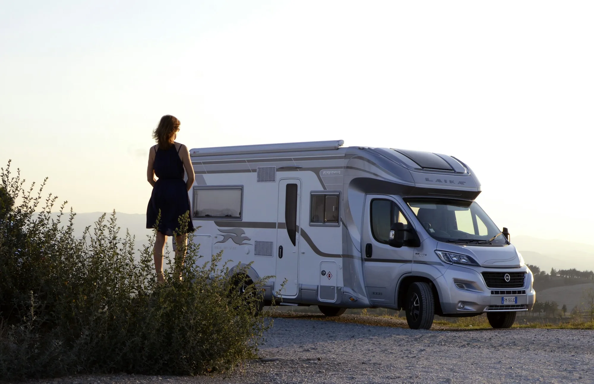 White motorhome parked at the edge of a hill while a traveler looks out over the view