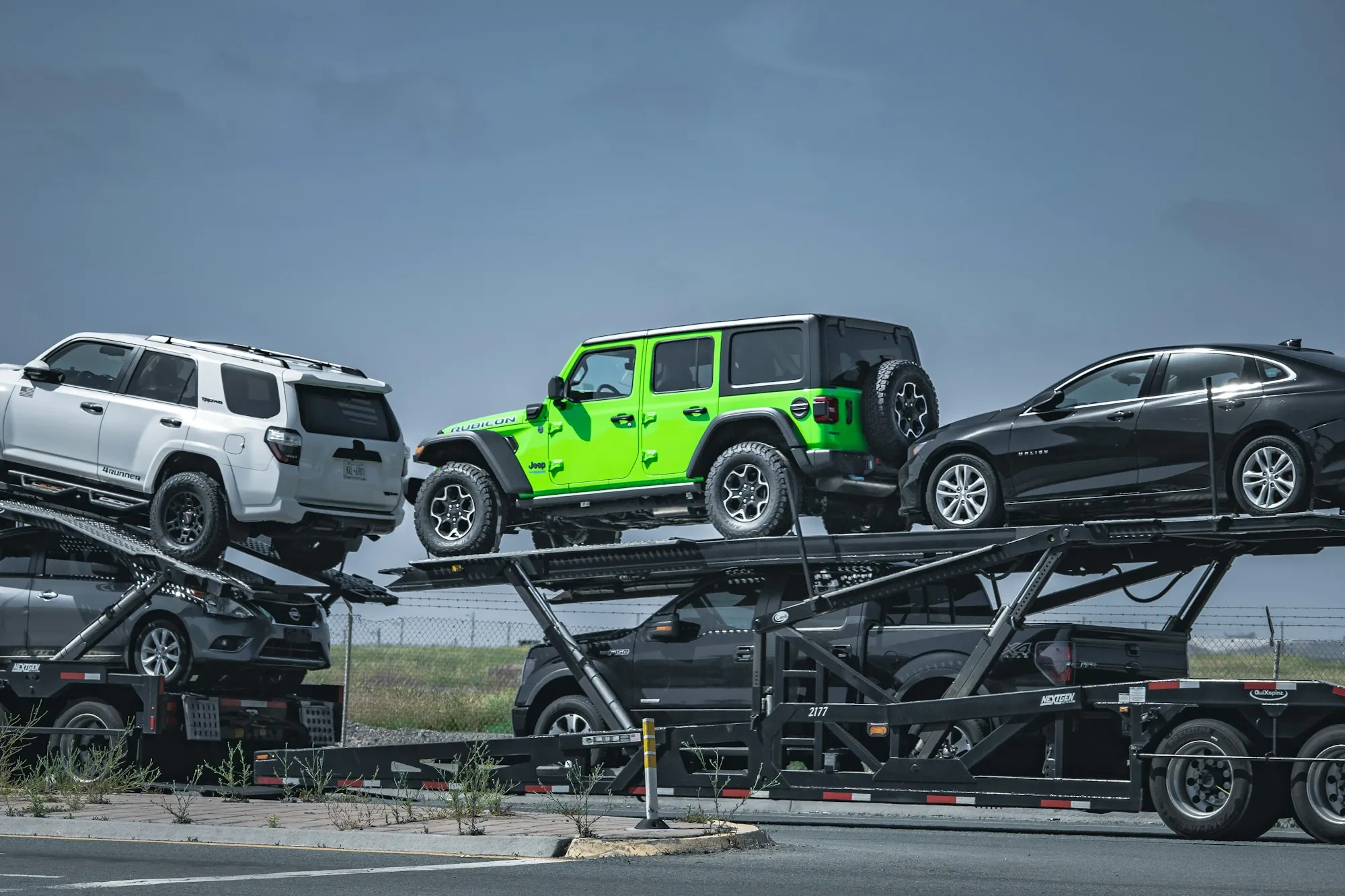 Car carrier truck loaded with SUVs and a bright green off-roader