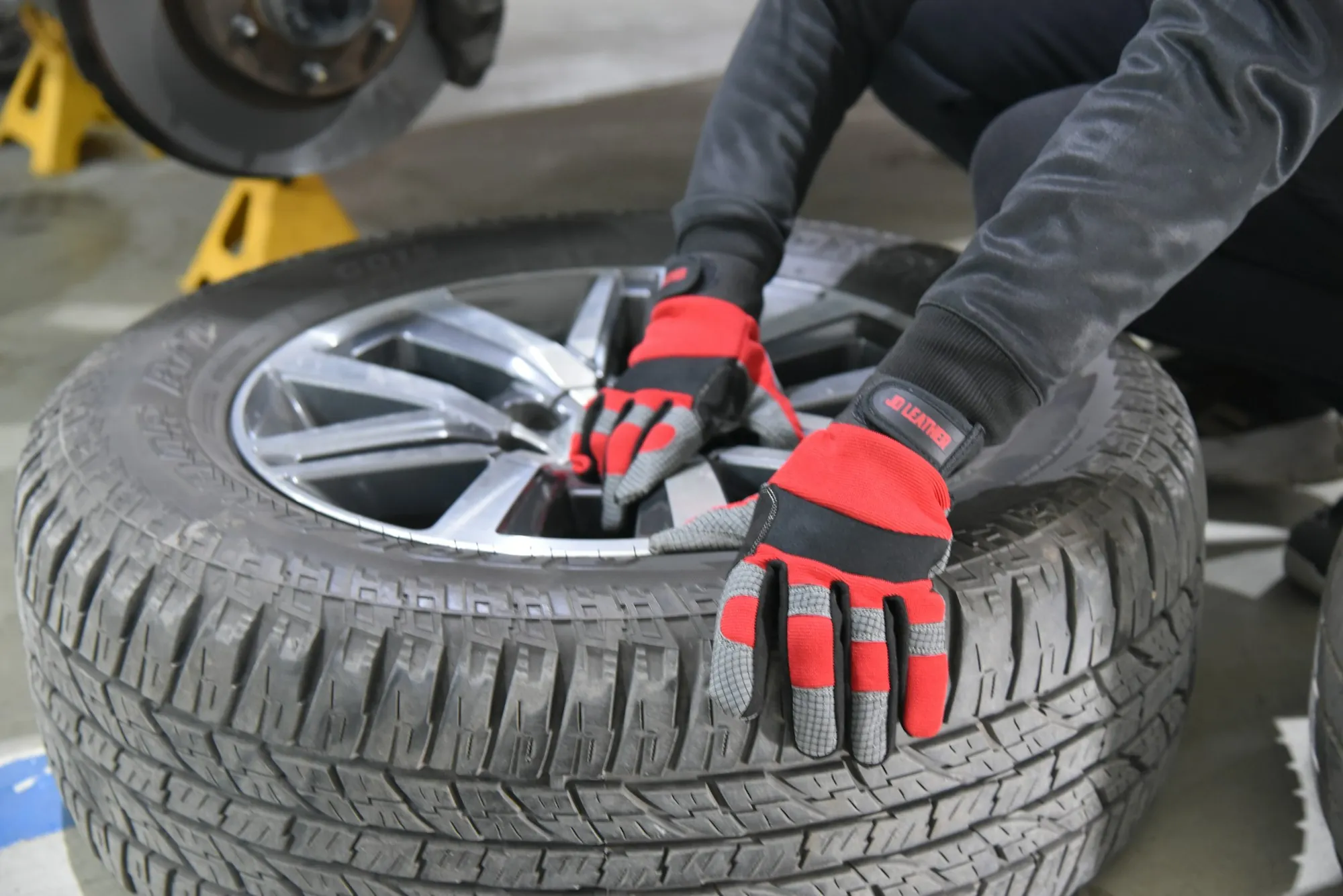 Gloved hands loosening the lug nuts on a car tire