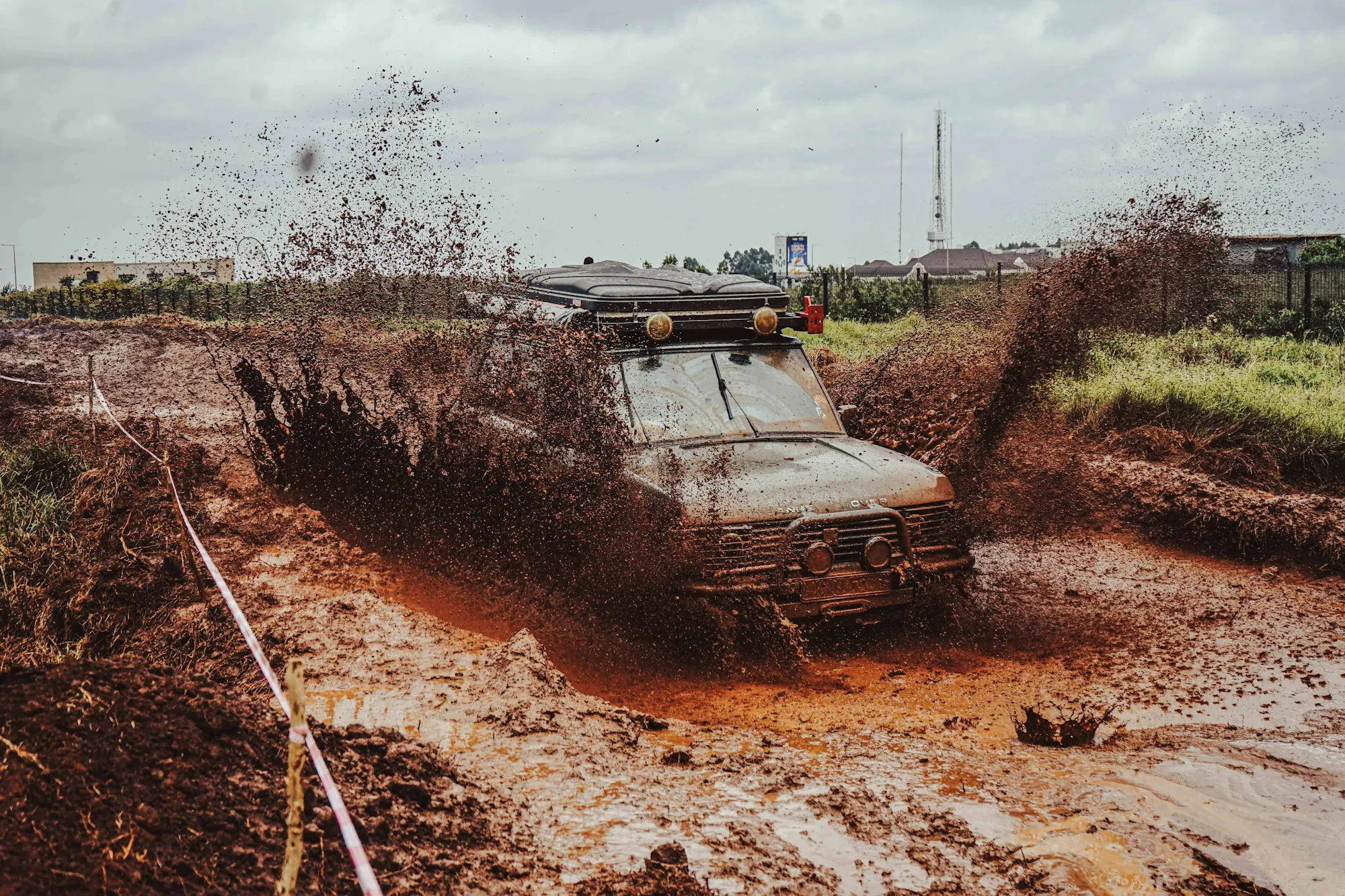 Off-road vehicle throwing up red mud while stuck on a flooded dirt track